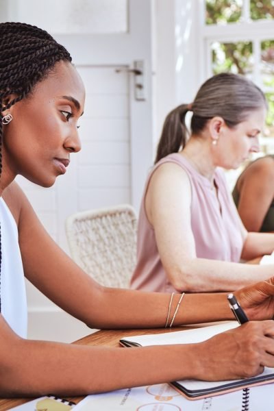 Black woman with business documents, writing at desk and women working together on audit report at